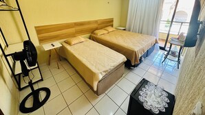 Habitación de hotel con dos camas, una mesita con mantel de encaje, un ventilador y vistas al exterior.