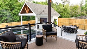 En udendørs terrasse med fletmøbler, en pool og en træterrasse.