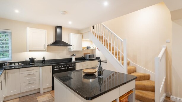 A modern kitchen with white cabinets, a black countertop, and a wooden island. - 1 Bed in Skelwith Bridge (oc-lr159) (Skelwith)