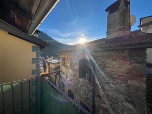 Um edifício de pedra com chaminé, varanda e vista para uma cordilheira.