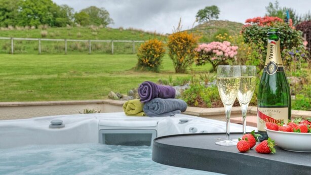 A hot tub with a bottle of champagne and glasses, surrounded by towels and strawberries. - 5 Bed in Taynuilt (oc-ca008) (Kilchrenan)