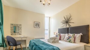 Een hotelkamer met een bed, een bureau, een stoel, een spiegel en een decoratief object aan de muur.
