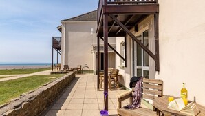 Ein Hotel am Meer mit Sitzgelegenheiten im Freien, einer Steinmauer und Blick auf den Ozean.