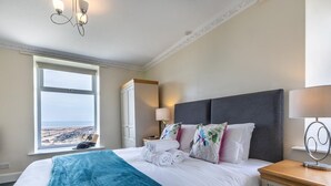 Habitación de hotel con cama, ventana con vistas, armario y mesita de noche con lámpara.