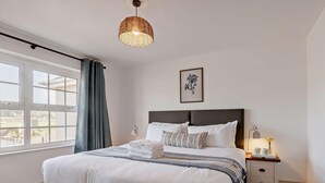 A neatly made bed with white linens, a dark headboard, and a bedside table with a lamp. - 3 Bed in Braunton (oc-87753) (Croyde)