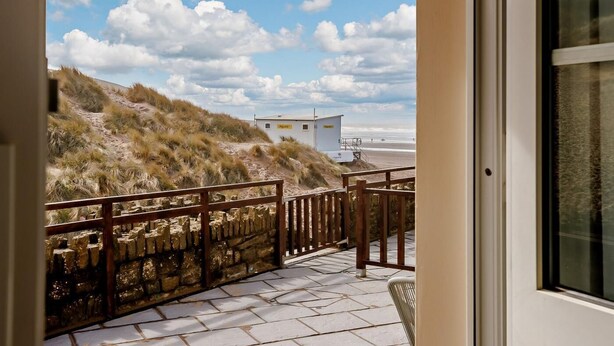 A stone pathway leading to a beach with a lifeguard station in the background. - 3 Bed in Braunton (oc-87754) (Croyde)
