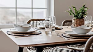 A dining table set with white bowls, glasses, and a woven basket with a plant. - 3 Bed in Braunton (oc-87754) (Croyde)
