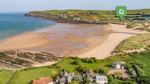 An aerial view of a coastal area with a beach, houses, and a green landscape. - 3 Bed in Braunton (oc-87754) (Croyde)