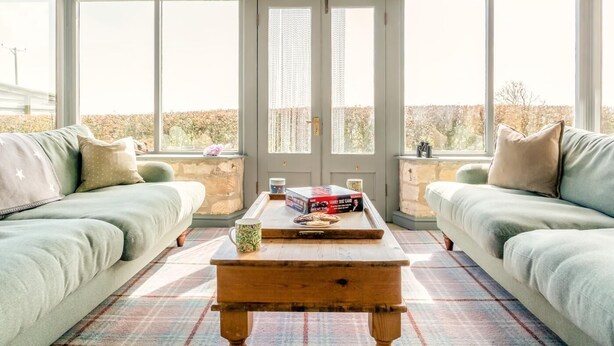 Ein Wintergarten mit zwei Sofas, einem Couchtisch und Blick auf einen Garten.