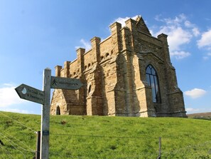A stone building with a pointed arch window and a signpost indicating directions to nearby locations. - 2 Bed in Bridport (oc-dc191) (Askerswell)