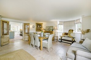 A spacious room with a dining area, a sofa, and a decorative horse sculpture.