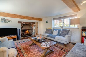 A living room with a fireplace, a sofa, a coffee table, and a television.