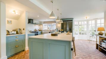 A kitchen with a central island, a dining area with a table and chairs, and a view through large windows.