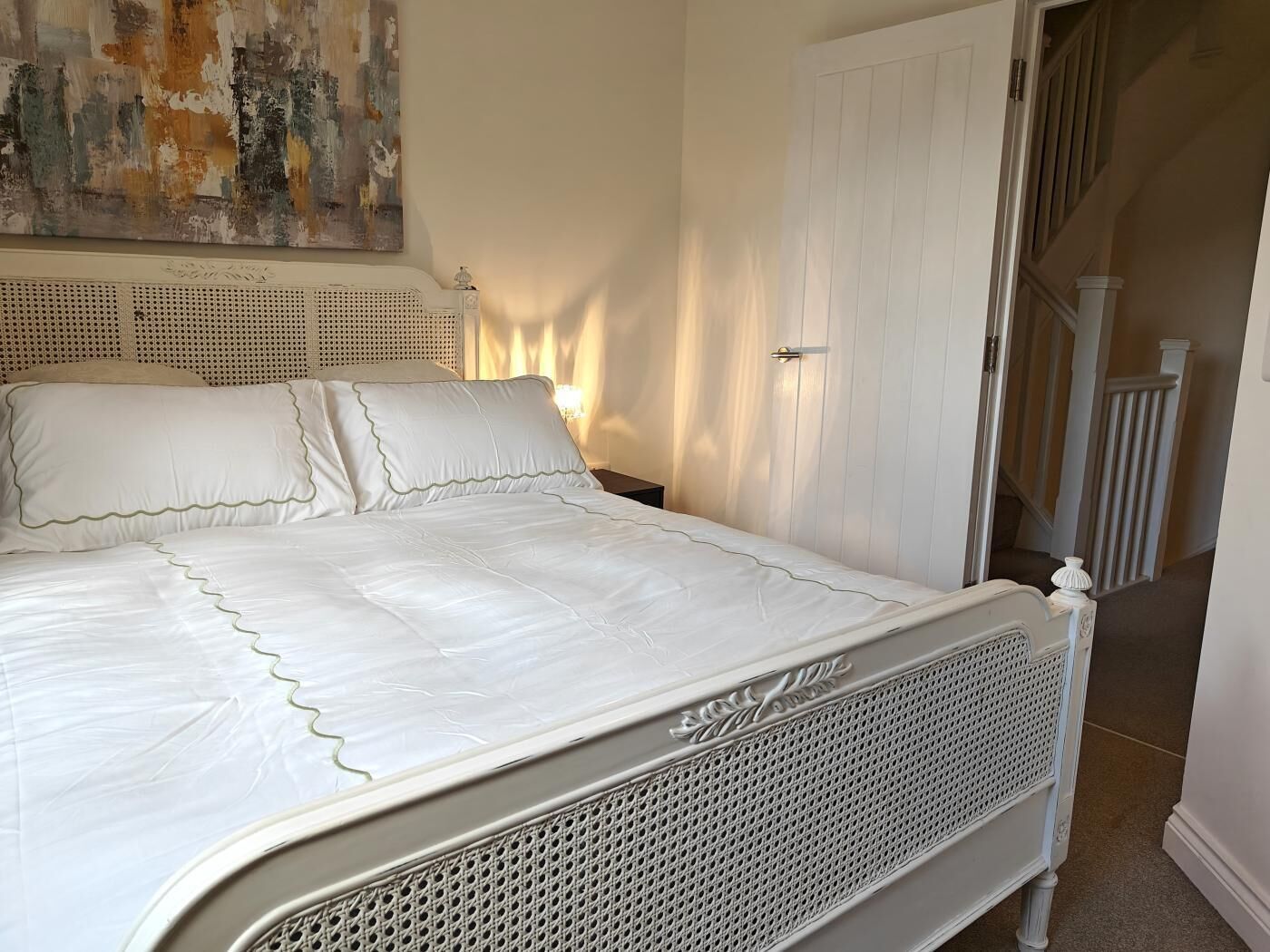 Un lit avec une tête de lit blanche, un matelas blanc et un cadre de lit blanc.
