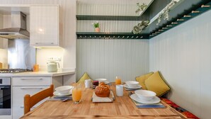 Un comedor con una mesa de madera, sillas y una disposición para el desayuno, que incluye croissants y jugo de naranja.