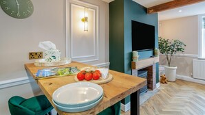 A modern kitchen with a wooden table, a green clock, and a fireplace. - 2 Bed in Thornton (oc-h36043) (Thornton)