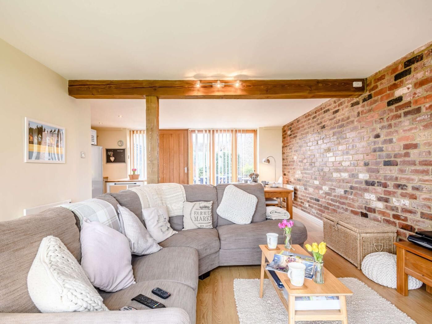 A cozy living room with a sectional sofa, a wooden coffee table, and a brick wall.