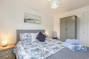 Ein Schlafzimmer mit Bett, Nachttisch, Lampe und Kleiderschrank.