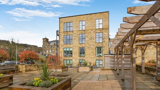 A courtyard with a stone building, wooden pergola, and flower beds. - 2 Bed in Haworth (oc-c37865) (Haworth)