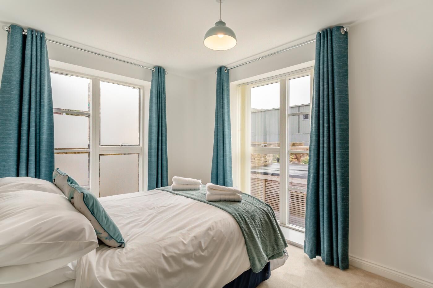 A bedroom with a bed, a window, and curtains.