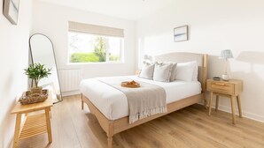A bedroom with a bed, bedside tables, a mirror, a window with blinds, and a view of greenery outside. - 4 Bed in Rock (oc-l50184) (Rock)