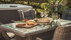 Ein Tisch mit Glasplatte, eine Champagnerflasche, zwei Weingläser, eine Salatschüssel, ein Brotlaib und eine dekorative Vase mit Blumen.