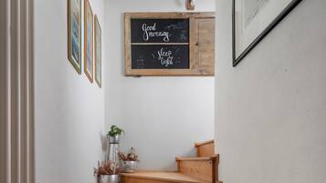 A staircase with a wooden handrail, a small table with potted plants, and a chalkboard with 'Good Morning' and 'sleep tight' written on it.
