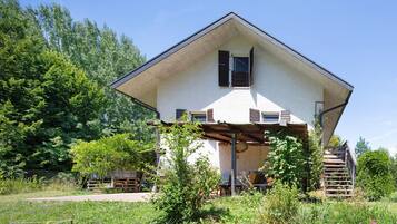 A two-story house with a sloped roof, a wooden deck, and a staircase leading to the upper floor.