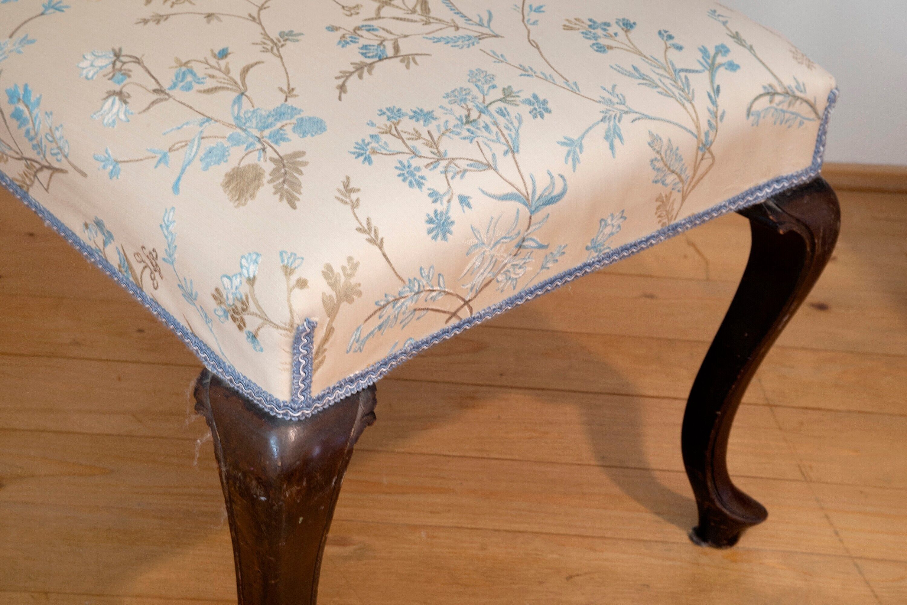 A chair with a floral upholstery pattern and a wooden frame.