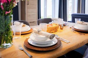 A dining table set with plates, bowls, cutlery, and a fruit basket. - MeerNah Grömitz Apartment 6. Family-friendly. Infrared cabin. Patio (Grömitz)
