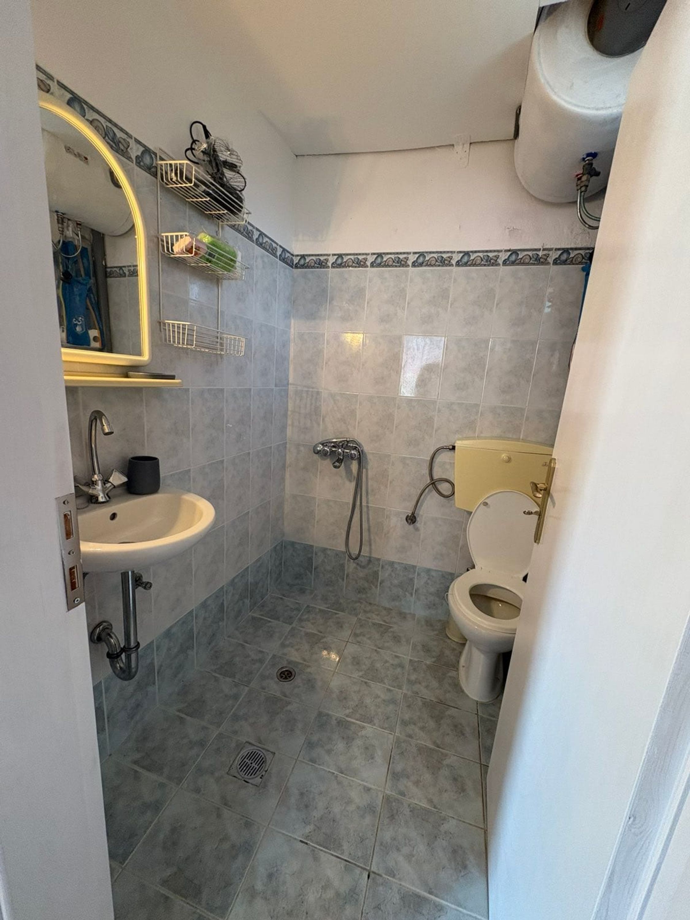 Un baño con lavamanos, inodoro, ducha y un espejo con toallero.