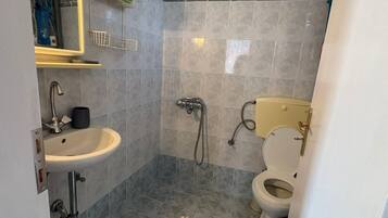 Un baño con lavamanos, inodoro, ducha y un espejo con toallero.