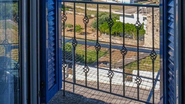 A balcony with a metal railing and a view of the sea and buildings. - Breeze - Getaway in Samos w Serene Sea View (Samos)