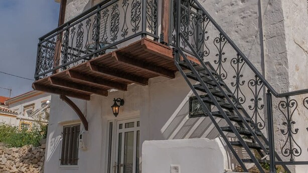 Ein weißes Gebäude mit einem Balkon, einer Holztreppe und einer gepflasterten Straße.