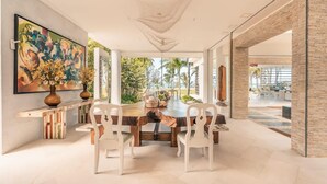 A dining area with a large table, white chairs, and a colorful abstract painting on the wall. - So Exclusive Beachfront Villa at Las Terrenas (Las Terrenas)