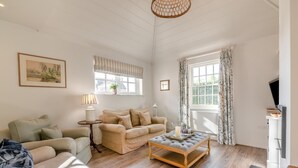 A living room with a sofa, a coffee table, a lamp, and a television. - 2 Bed in Stoke (oc-c41361) (Stoke)