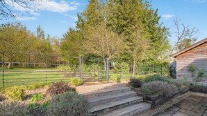 A wooden staircase leading to a wooden building, surrounded by a metal fence and a grassy field. - 2 Bed in Stoke (oc-c41361) (Stoke)