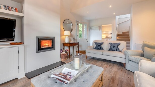 A living room with a fireplace, a sofa, a television, and a bookshelf. - 2 Bed in Stoke (oc-c41361) (Stoke)