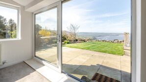 A room with a sliding glass door leading to a patio with a lawn and stone wall. - 3 Bed in Ravenscar (oc-w41046) (Ravenscar)