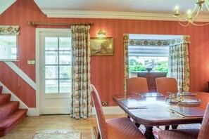 Een eetruimte met een tafel voor vier personen, een trap en uitzicht op groen.