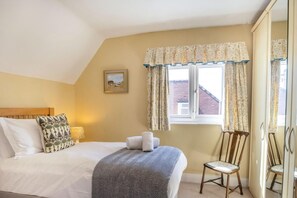 A bedroom with a bed, a chair, a window with curtains, and a painting on the wall. - 4 Bed in Beadnell (oc-t41388) (Beadnell)