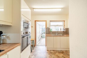 A kitchen with a microwave, oven, and sink, wooden countertops, and a view to the outside. - 2 Bed in Dalrymple (oc-b40270) (Dalrymple)