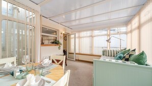 A dining area with a table set for two, a sofa, and a window with blinds. - 2 Bed in Dalrymple (oc-b40270) (Dalrymple)