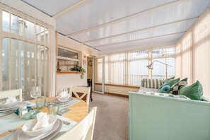 A dining area with a table set for two, a sofa, and a window with blinds. - 2 Bed in Dalrymple (oc-b40270) (Dalrymple)