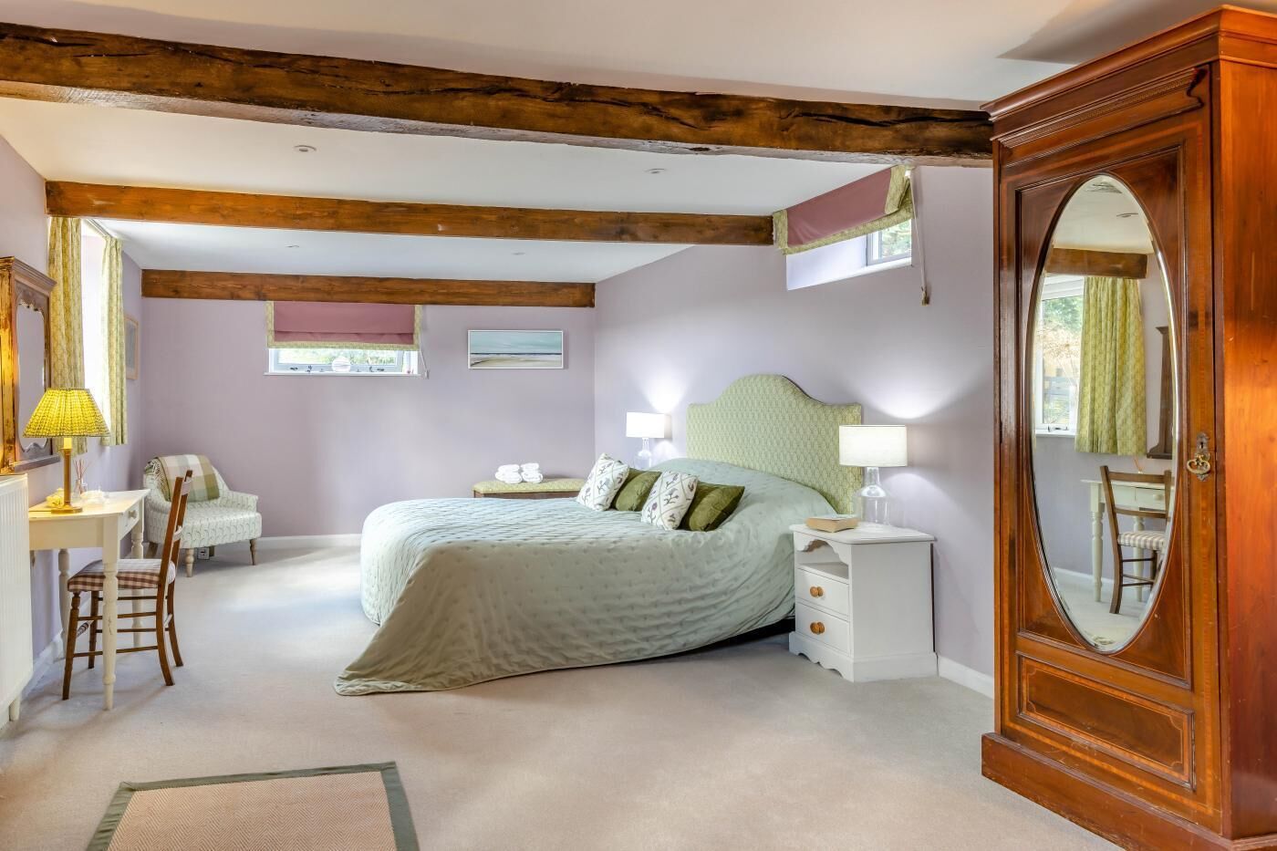 Une chambre à coucher comprenant un lit, des tables de chevet, un miroir, un bureau et une chaise.