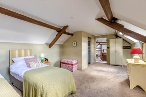 A bedroom with a sloped ceiling, a bed, a nightstand, a lamp, a small table, and a wardrobe. - 2 Bed in Dulverton (oc-h34793) (Brushford)