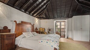 Een slaapkamer met een houten bed, een nachtkastje, een dressoir en een garderobe.