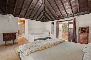 Una camera da letto con un letto, una cassettiera in legno, uno specchio e una ventola a soffitto.