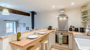 Una cocina moderna con encimeras de madera, horno integrado y un amplio ventanal.