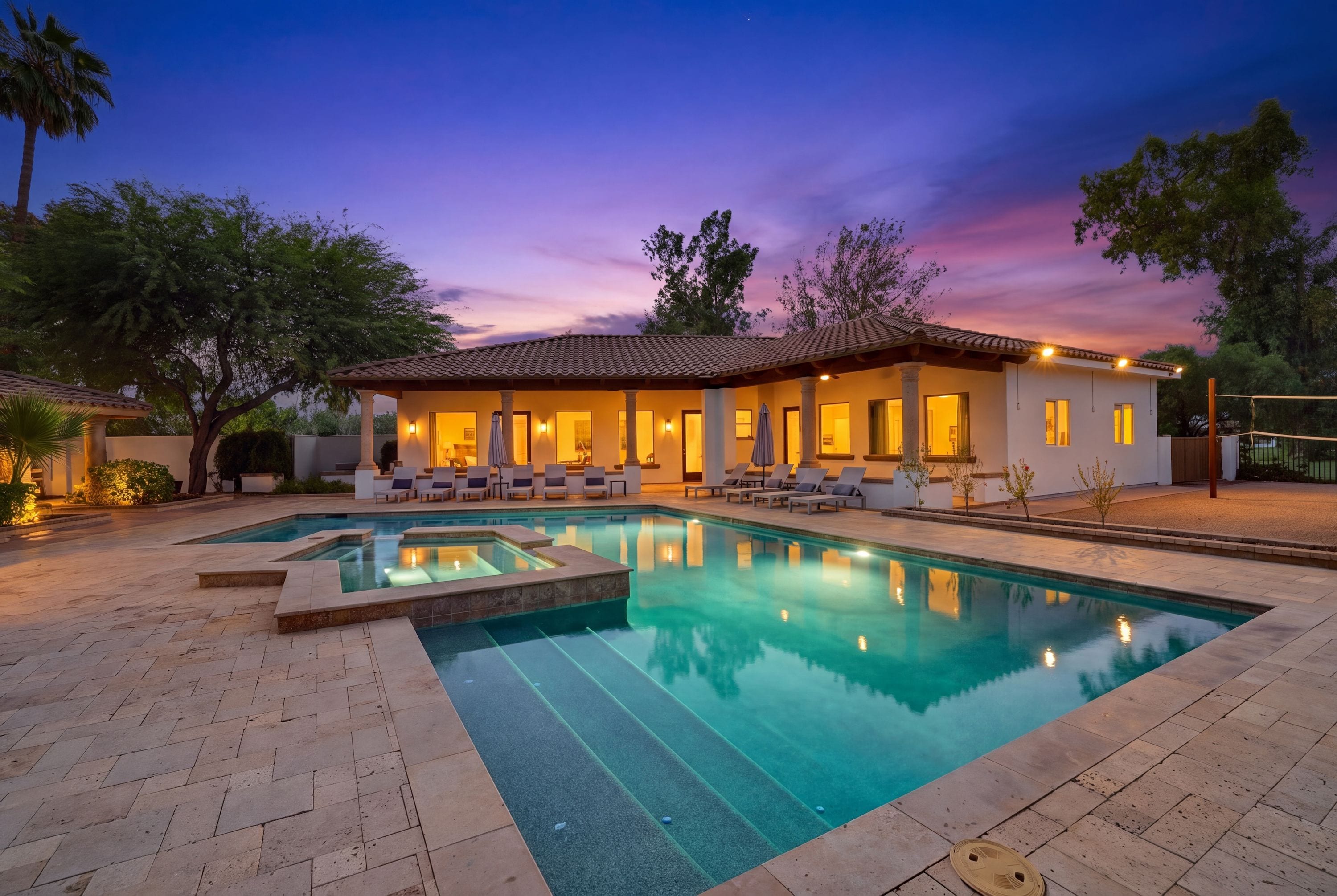 Resort-style pool and spa with glowing patio at sunset